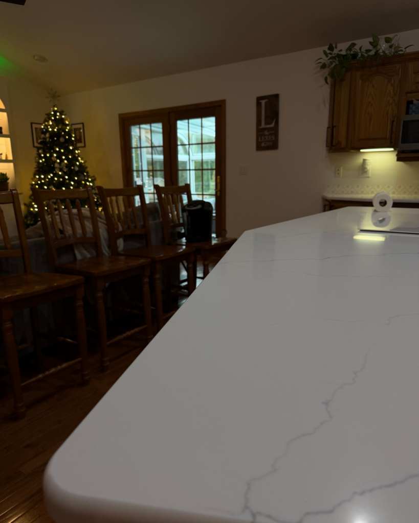 calacatta Miraggio quartz installed on large kitchen island with warm wood cabinetry showing full surface luminosity